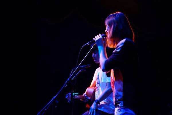 Xiao singing into a microphone on a dark stage